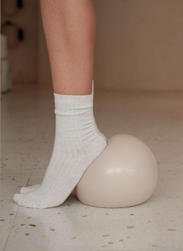 Feet in white socks balancing on a cream pilates massage ball
